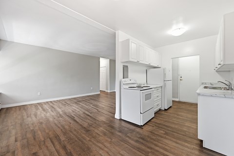 A kitchen with white appliances and wooden floors.