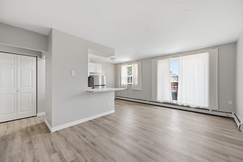 A spacious living room with wooden flooring and white walls.
