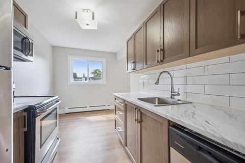 A kitchen with a stainless steel refrigerator, a stainless steel oven, and a marble countertop.