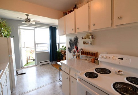 A white stove top oven with four burners is in a kitchen with white cabinets.
