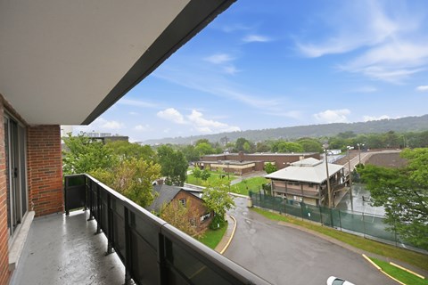 A balcony overlooks a wet street and buildings.