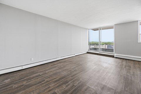 A room with wooden flooring and a large window overlooking a field.