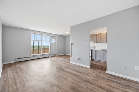 A spacious room with wooden flooring and a large window.