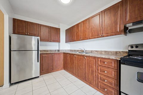 A kitchen with wooden cabinets and a stainless steel refrigerator.