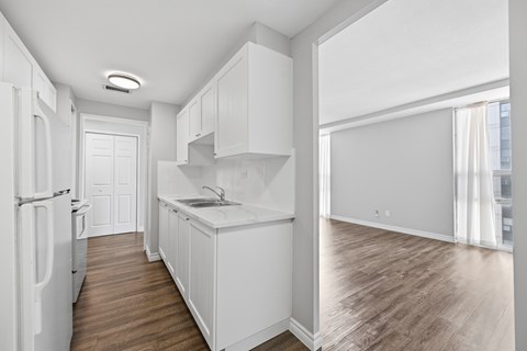 A kitchen with white cabinets and a white fridge.