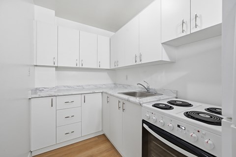 A white kitchen with a stove and cabinets.