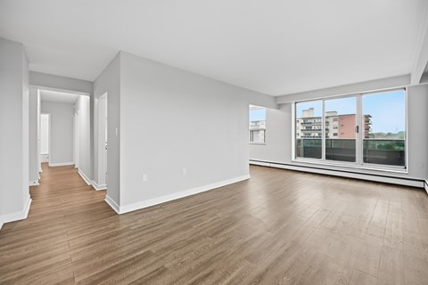 A spacious room with wooden flooring and large windows.