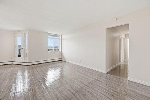 A spacious room with wooden flooring and a view of the outside through a large window.