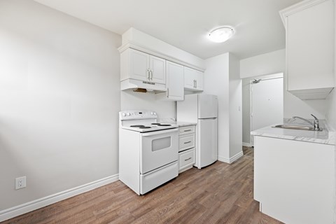 A white kitchen with wood flooring and white appliances.
