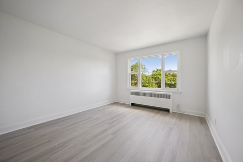 A room with a window and a radiator on the floor.