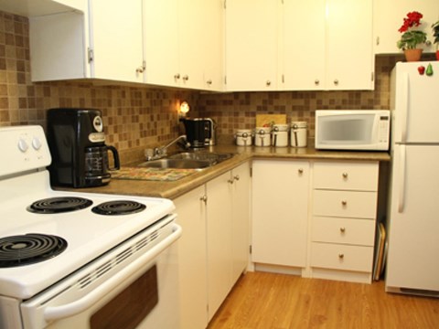 A kitchen with a white stove and white cabinets.