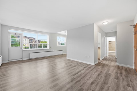 A spacious room with light wood flooring and large windows.
