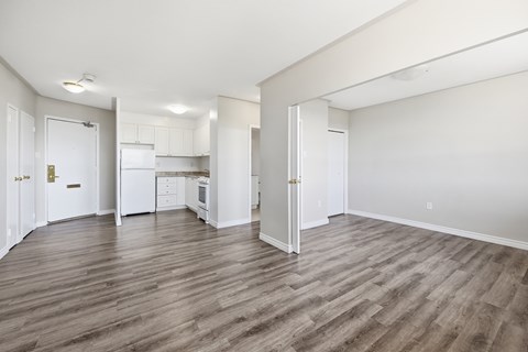 A spacious room with wooden flooring and white walls.
