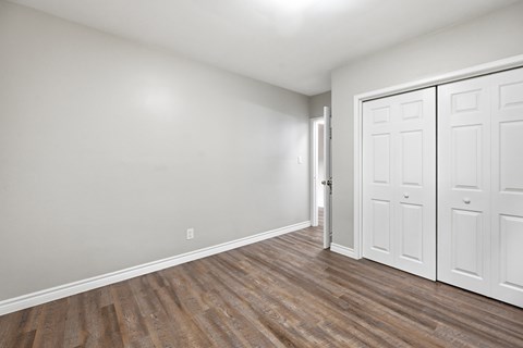 A room with a white door and wooden flooring.