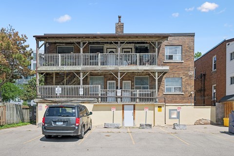 A grey car is parked in a parking lot in front of a wooden building.