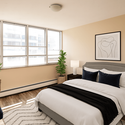 A bedroom with a large bed and a potted plant.