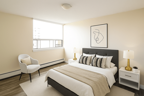 A bedroom with a bed, chair, and lamp.