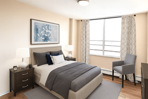 A bedroom with a large bed, a nightstand with a lamp, and a chair by the window.
