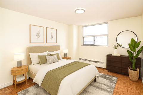 A bedroom with a bed, nightstand, and a plant.