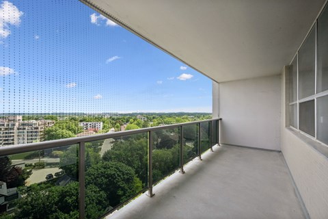 A balcony with a view of the cityscape and trees.