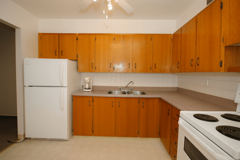 A kitchen with white appliances and wooden cabinets.
