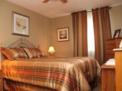 A bedroom with a bed, nightstand, and pictures on the wall.