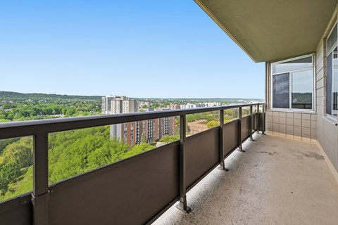 A balcony with a view of a cityscape and greenery.