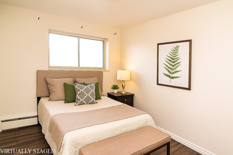 A bedroom with a bed, nightstand, and a framed leaf picture on the wall.