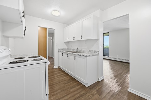 A kitchen with white cabinets and a white stove top oven.