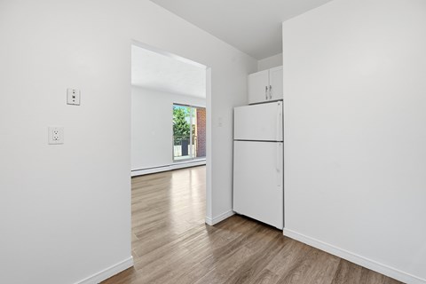 A white kitchen with a window and a wooden floor.