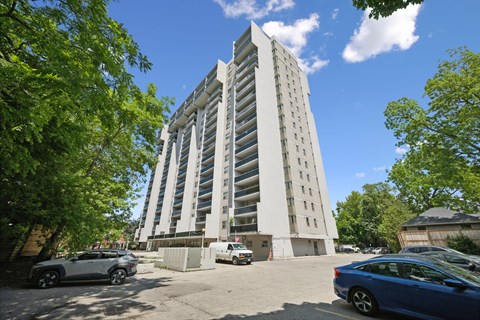 A tall white building with a parking lot in front of it.