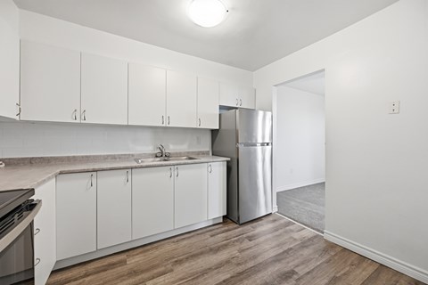 A kitchen with white cabinets and a stainless steel refrigerator.