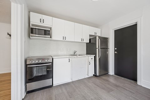 A kitchen with white cabinets and a black refrigerator.
