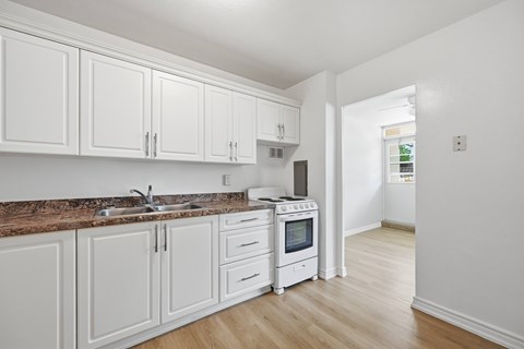 A kitchen with white cabinets and a brown countertop.