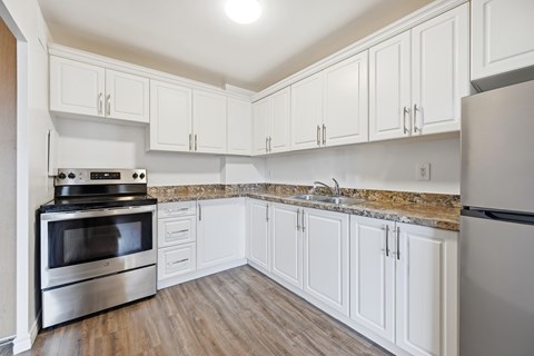 A kitchen with white cabinets and a granite countertop.