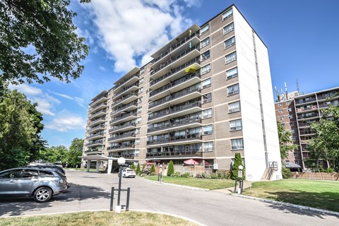 A tall residential building with a parking lot in front.