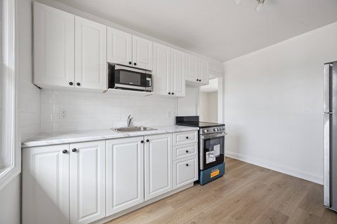A kitchen with white cabinets and a blue dishwasher.