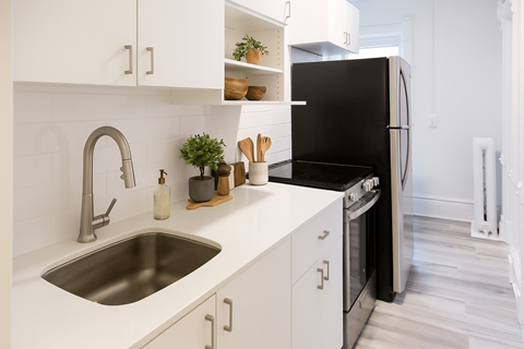 A modern kitchen with a black refrigerator and white cabinets.