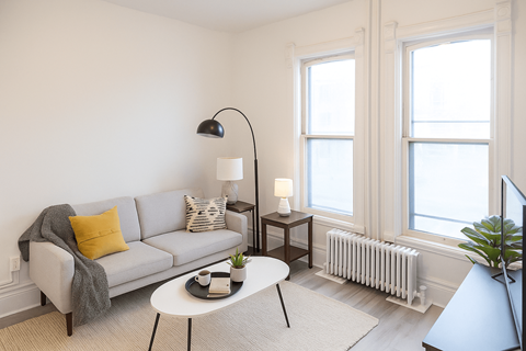 A living room with a grey couch, a white table, and a grey floor lamp.