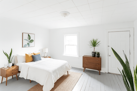 A white bedroom with a large bed and a wooden nightstand.