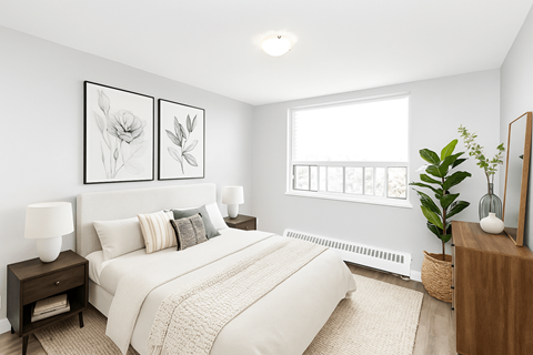 A bedroom with a large bed, two lamps, and a plant.