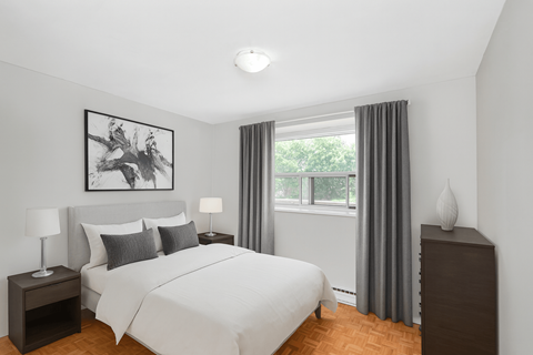 A bedroom with a large bed, a nightstand with a lamp, and a framed picture on the wall.