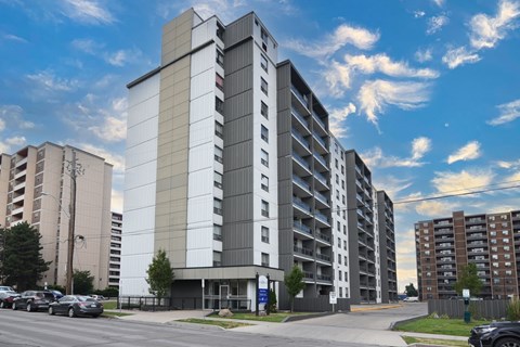 A large, modern apartment building with a parking lot in front.