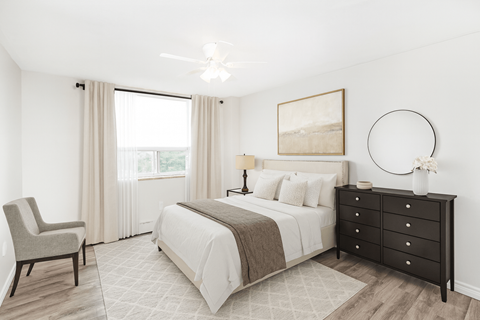 A bedroom with a large bed, a chair, and a painting on the wall.
