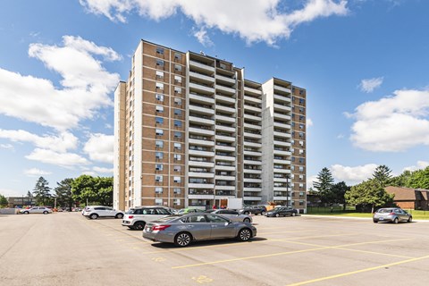 A parking lot with cars and a tall building in the background.