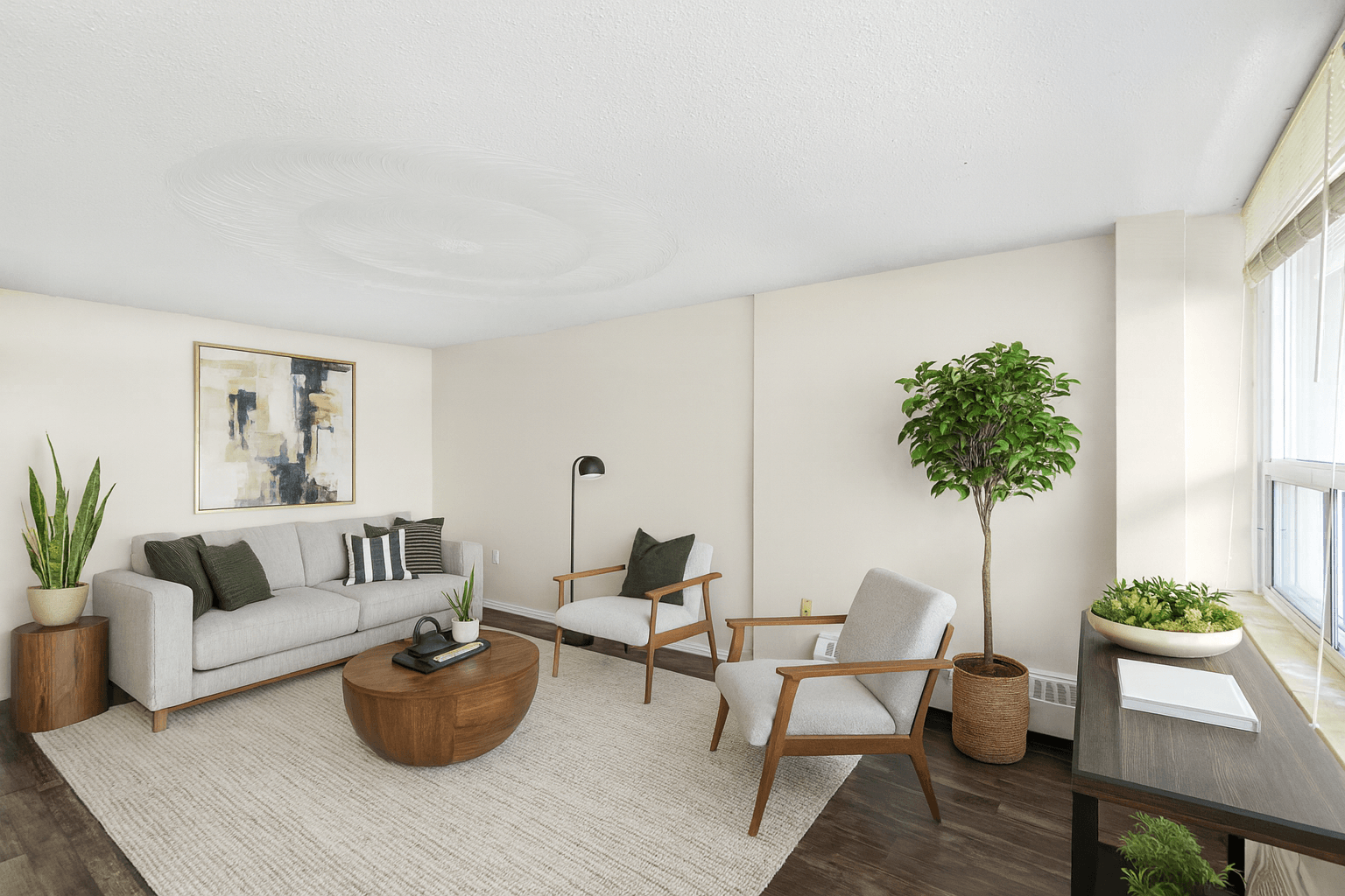 A living room with a grey couch, a wooden coffee table, a chair, a potted plant, and a painting on the wall.