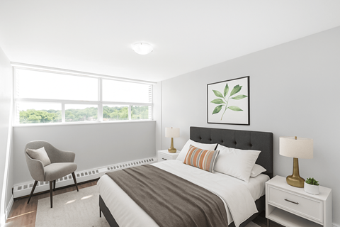 A bedroom with a large bed, a chair, and a window.