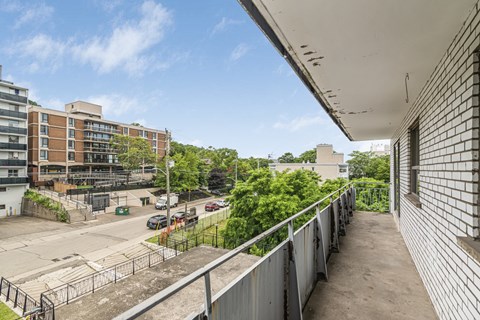 A view from a balcony looking down at a parking lot and buildings.