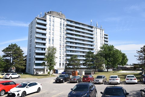 A parking lot with cars and a large white building in the background.
