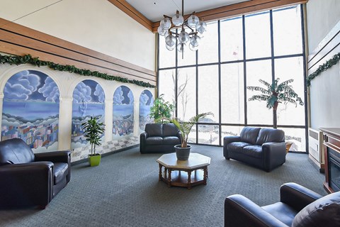 A living room with a large window and a painting on the wall.